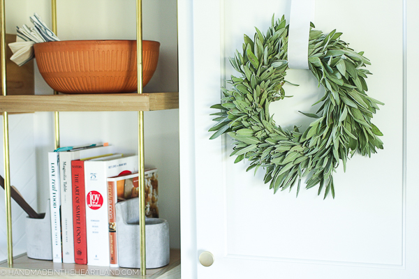 Fresh sage wreath hanging on cabinet in kitchen