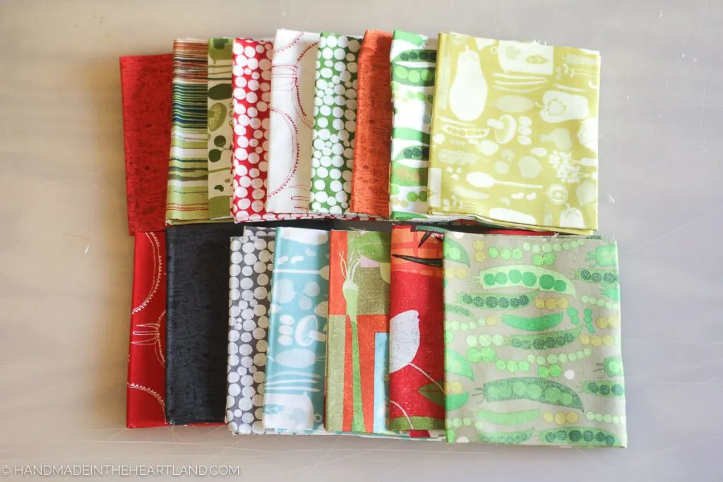 a picture of 16 different fabrics folded on a table. 