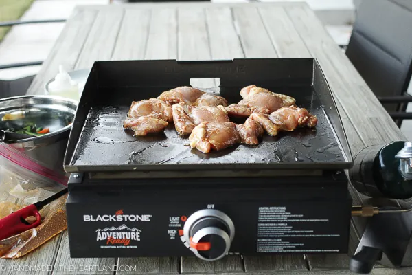 chicken thighs being cooked outdoor on a Blackstone griddle