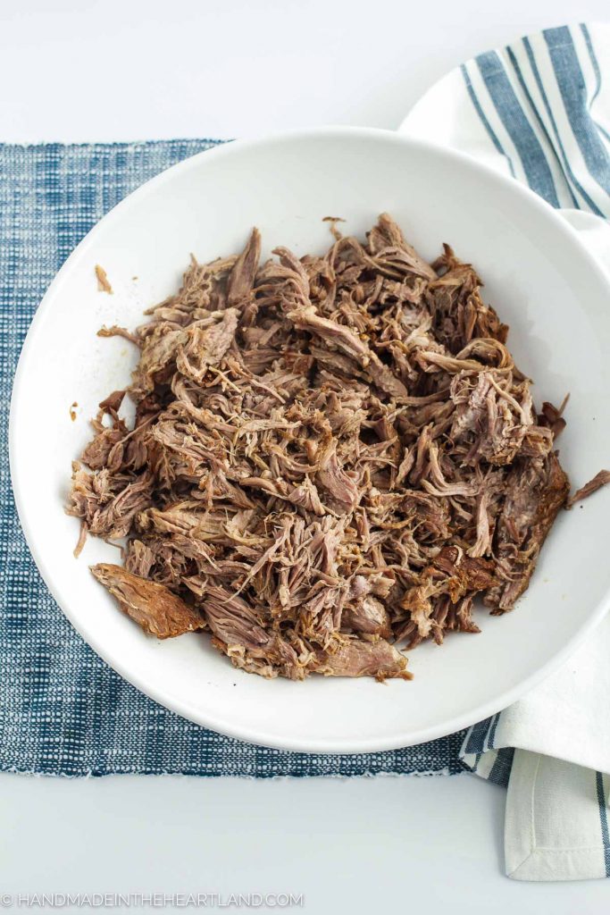 pulled pork being served in a large white bowl