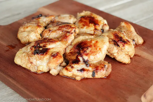 Cooked chicken thighs on wood cutting board