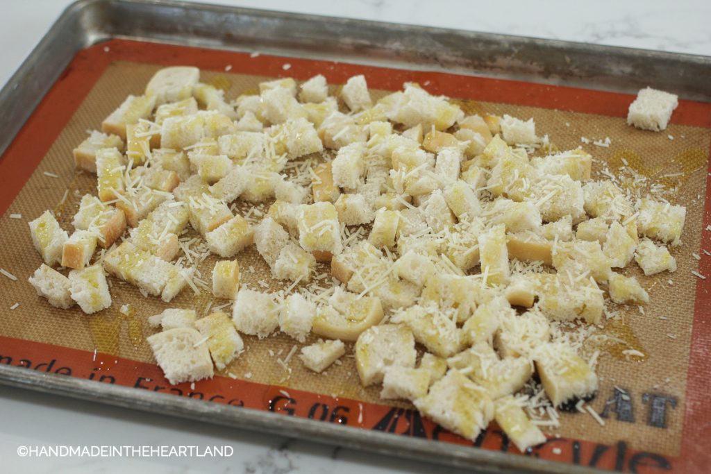 diced sourdough bread with olive oil and parmesan on a baking sheet