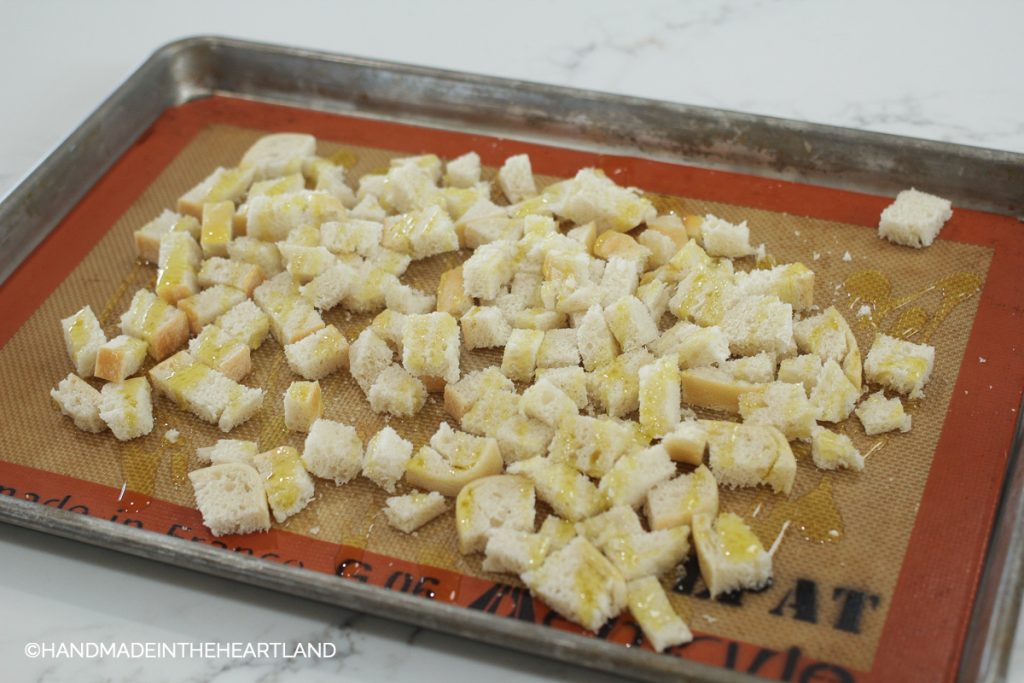 diced sourdough bread pieces on a baking sheet with olive oil drizzled on