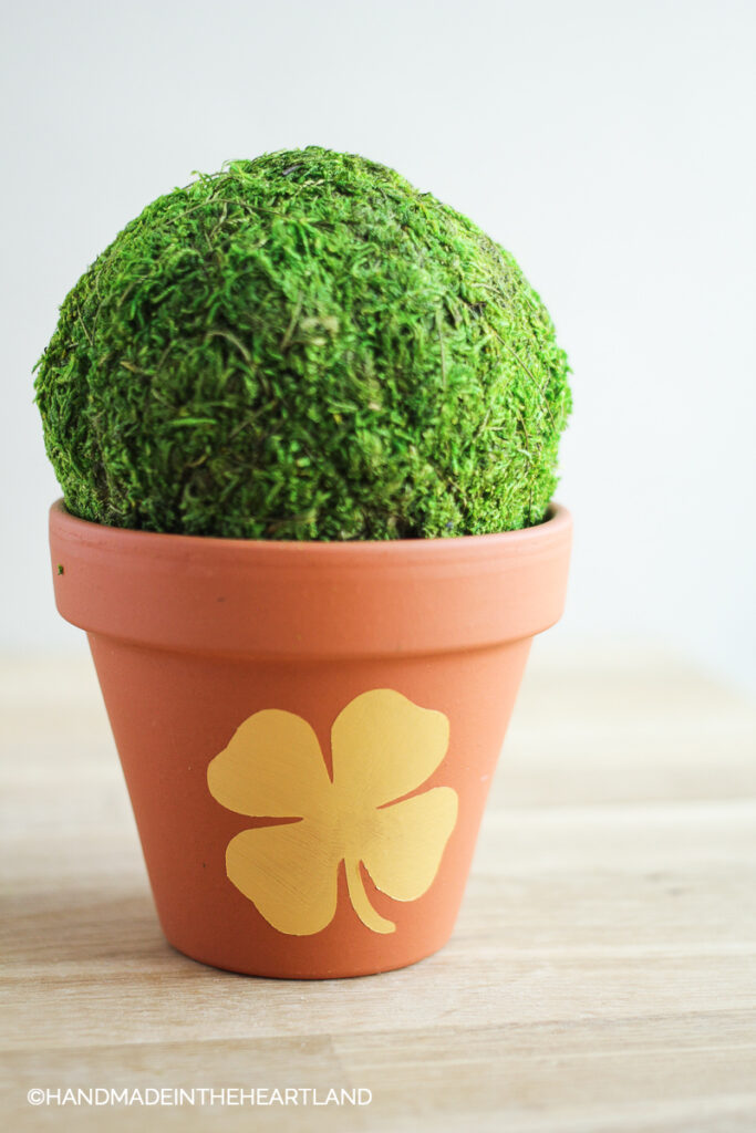 terracotta flower pot with painted four leaf clover with topiary green ball in it