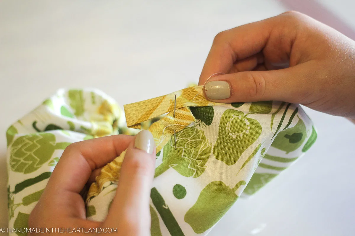 pinning the bias tape at the end to close the mixing bowl cover