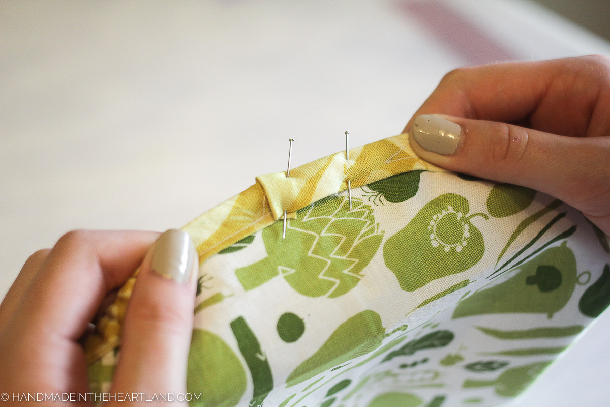 folding over the last side of bias tape to fully close the mixing bowl cover