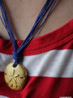 gold sand dollar polymer clay bead on blue string necklace