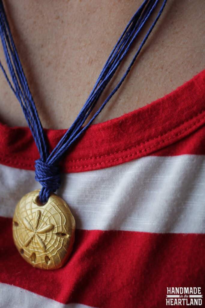 gold sand dollar polymer clay bead on blue string necklace