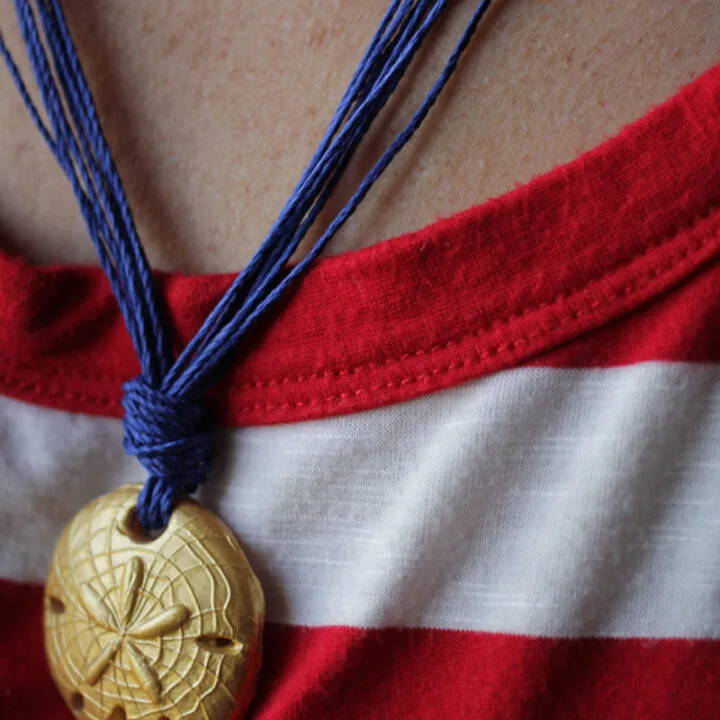 gold sand dollar polymer clay bead on blue string necklace