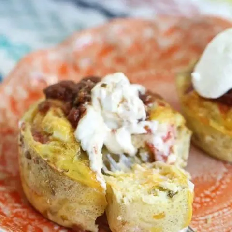 Egg muffin topped with salsa and sour cream on an orange plate