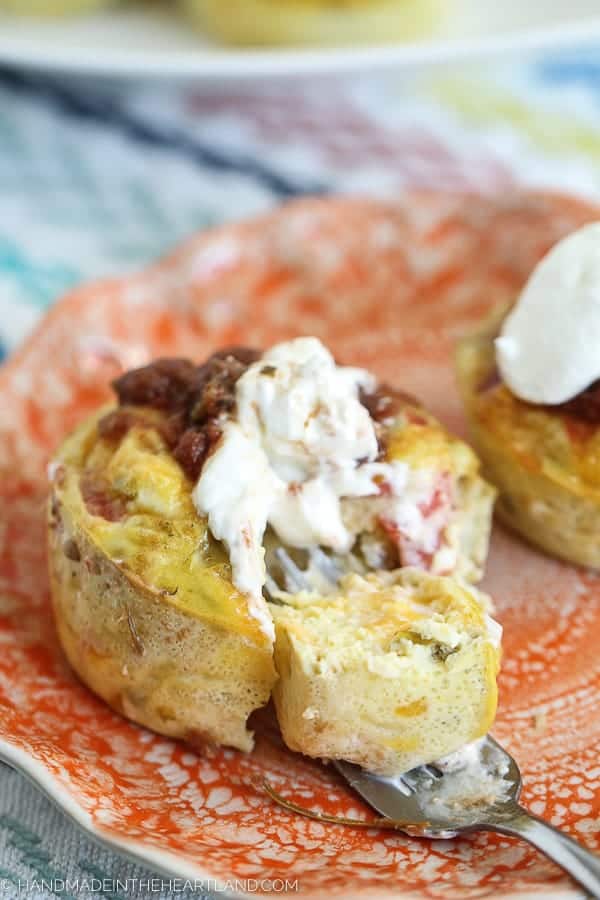 Egg muffin topped with salsa and sour cream on an orange plate