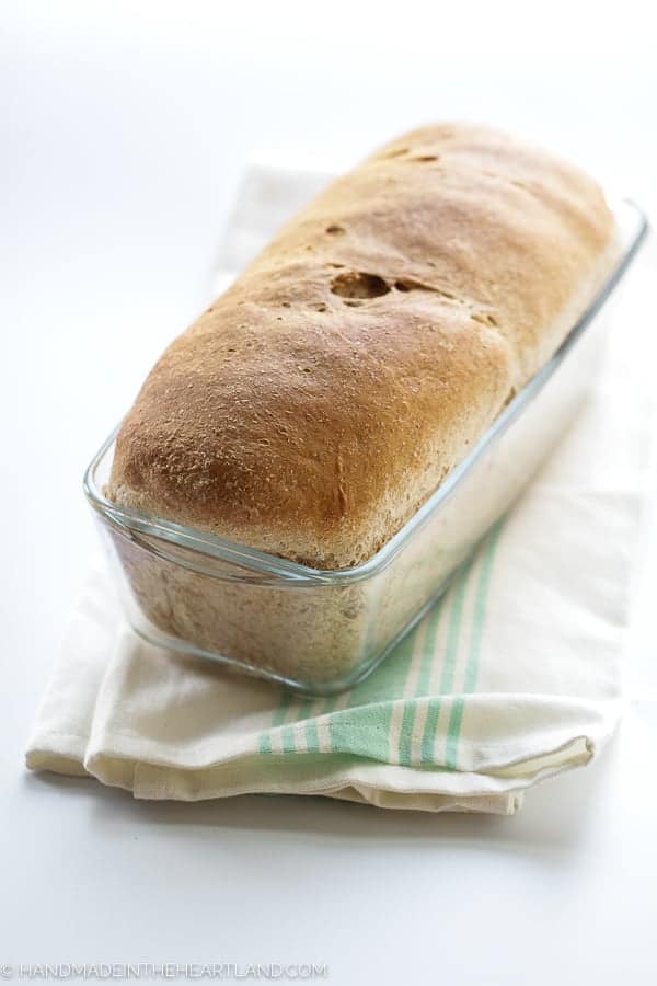 whole wheat loaf of bread in a glass bread pan
