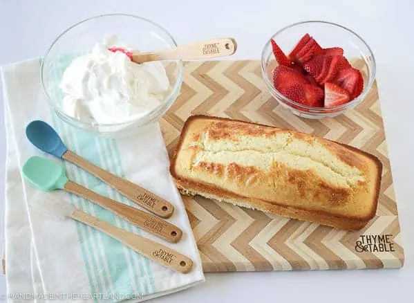 fresh made whipped cream, strawberry shortcake cake and fresh sliced strawberries ready to layer