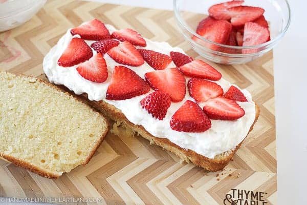 Placing strawberry slices on top of whipped cream layer on strawberry shortcake cake