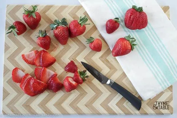 Strawberries being cut on a Thyme and Table chevron cutting board