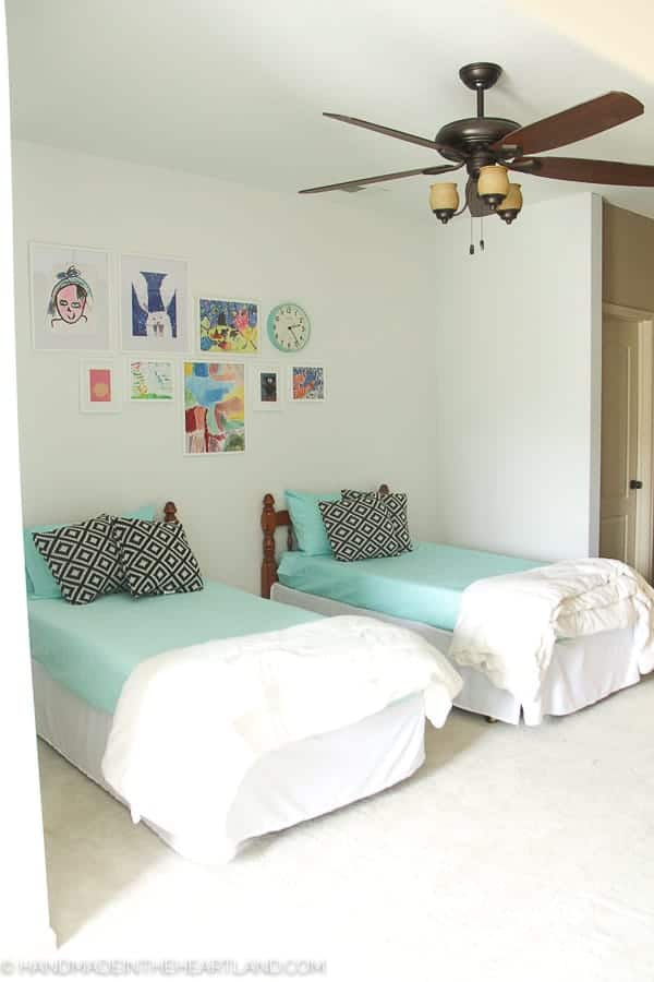 modern kids room with aqua bedding, black and white pillows and white framed kids artwork on the wall