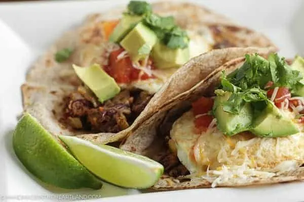 Delicious breakfast tacos with avocado, cilantro, red beans, tomatoes and eggs