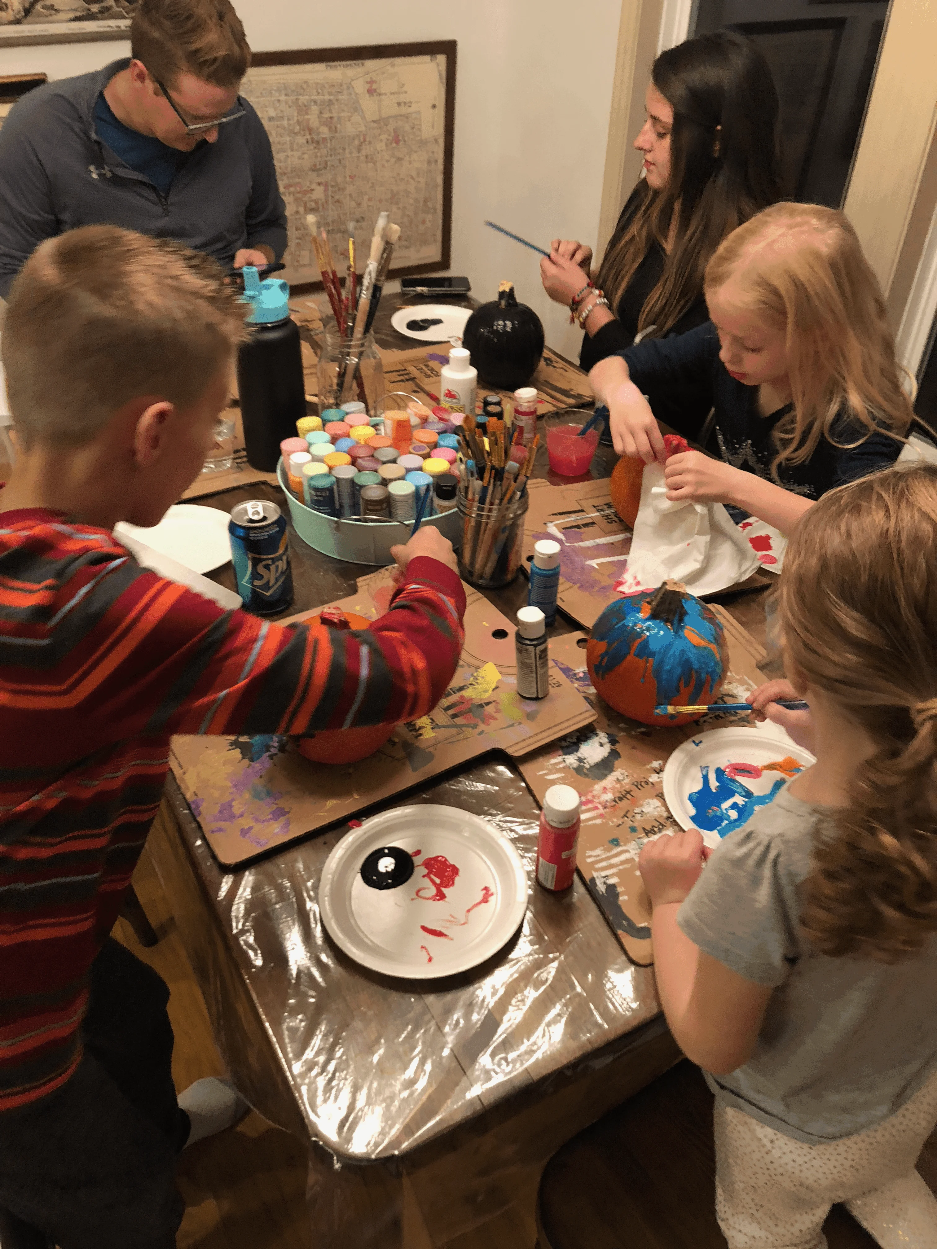 family gathered around kitchen table painting pumpkins