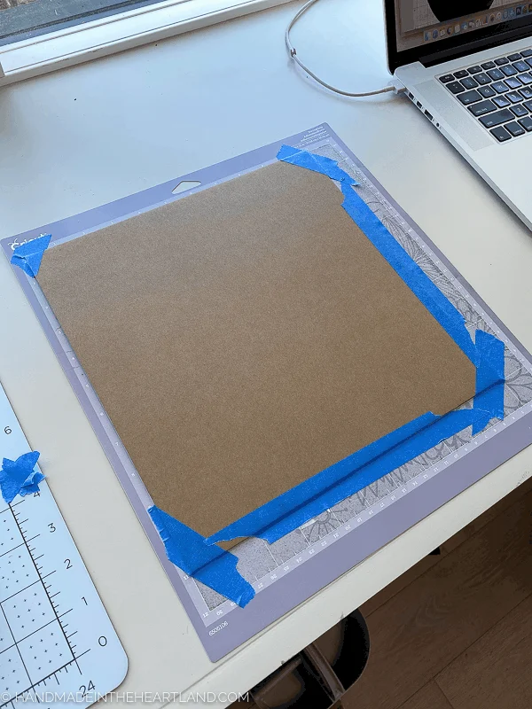 chipboard prepared on Cricut cutting mat with painters tape
