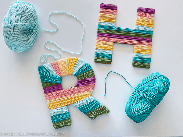 Chipboard cut letters wrapped in rainbow colored yarn stripes