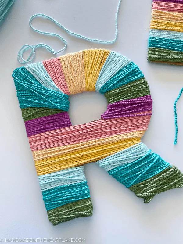Yarn wrapped letter in modern rainbow colors, made with the Cricut Maker, Cricut Chipboard and Cricut Knife Blade