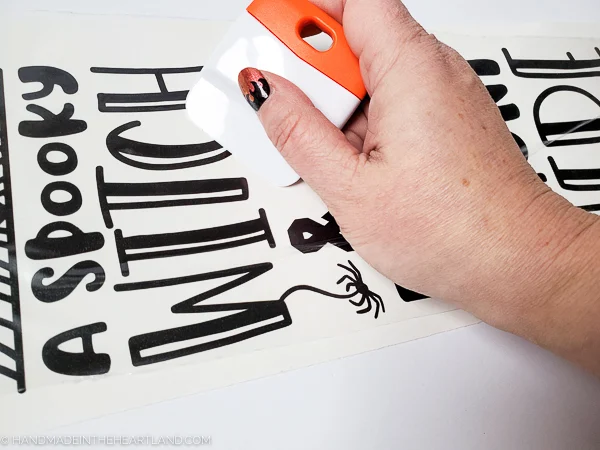 Using a spatula to transfer vinyl lettering