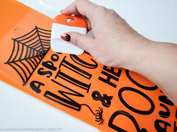 applying vinyl lettering to a diy halloween sign