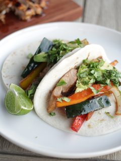 chicken and veggie fajitas on flour tortillas on white plate