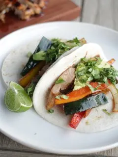 chicken and veggie fajitas on flour tortillas on white plate