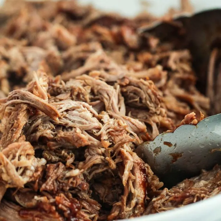 image of pulled pork with bbq sauce in a bowl with tongs to serve