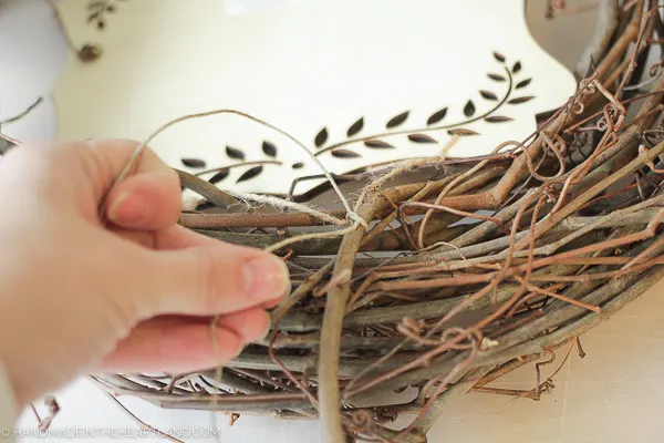 tying wood sign onto wreath