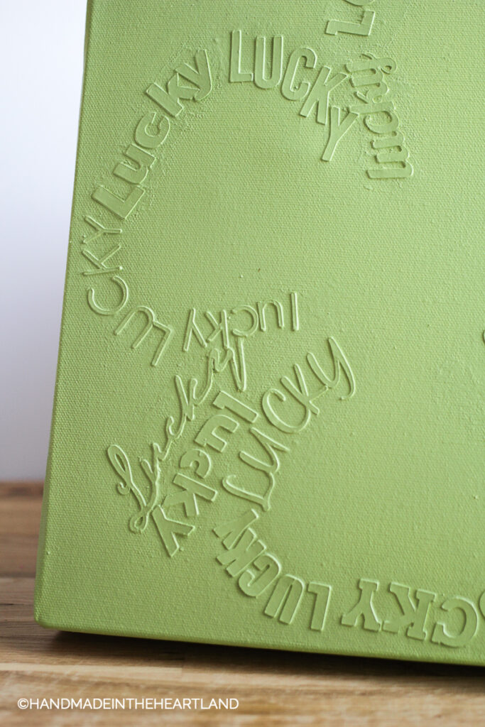 monochromatic green canvas with words Lucky in the shape of a 4 leaf clover