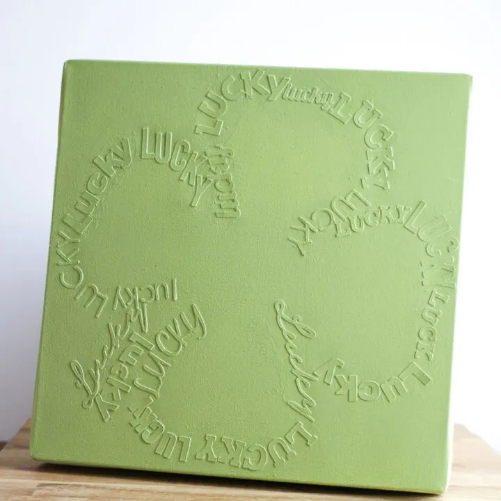 monochromatic green canvas with lucky writing in the shape of a 4 leaf clover