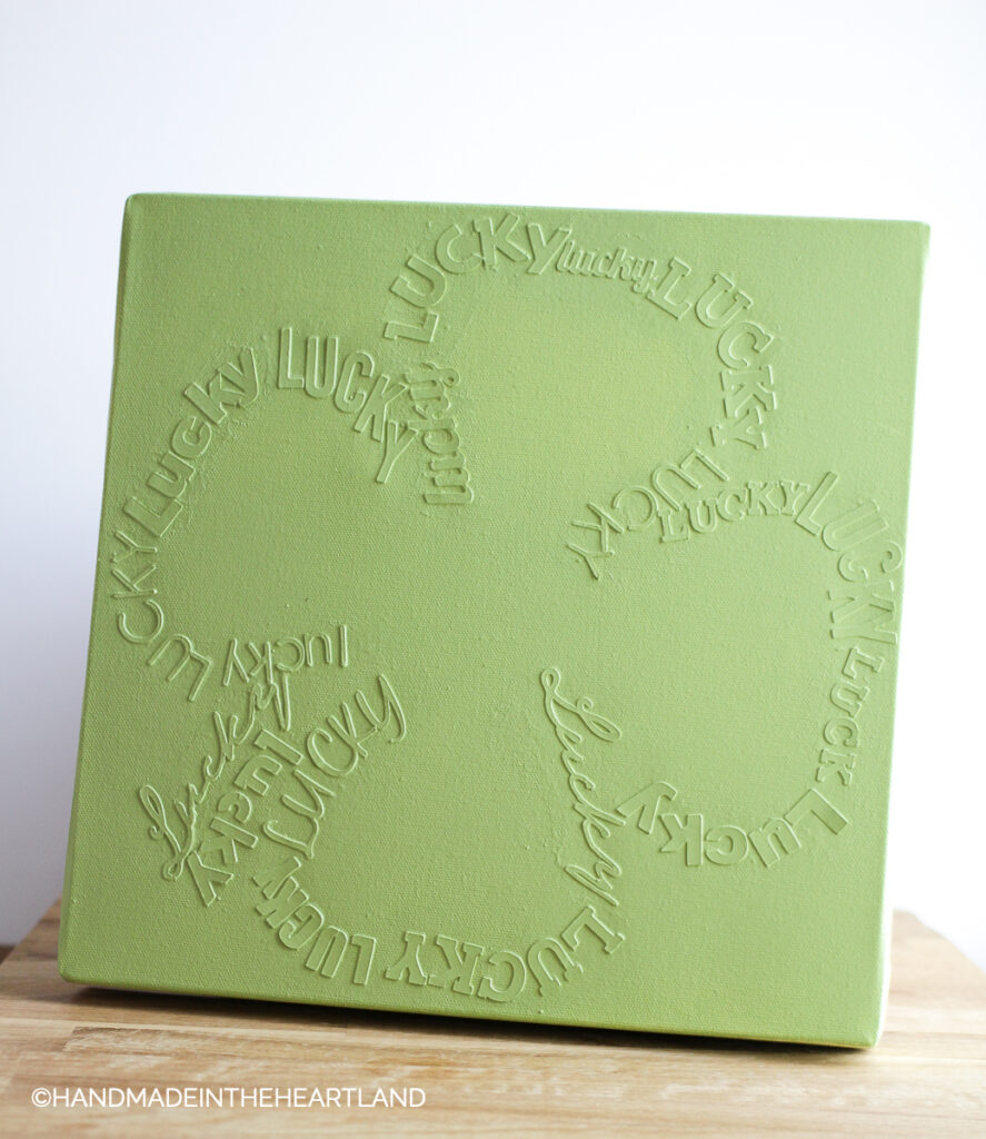 monochromatic green canvas with lucky writing in the shape of a 4 leaf clover