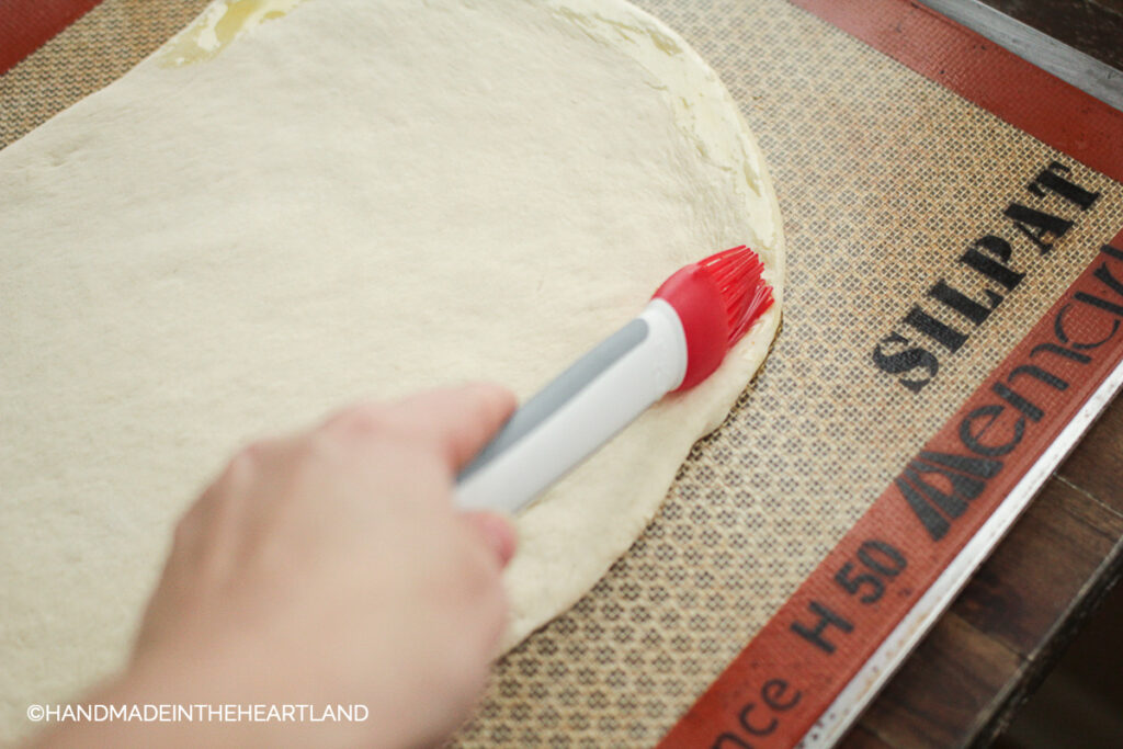 brushing olive oil onto pizza crust with a silicone basting brush