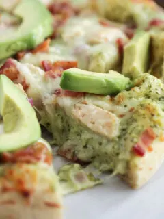 Pizza slice with melty cheese, chicken, and avocado on top