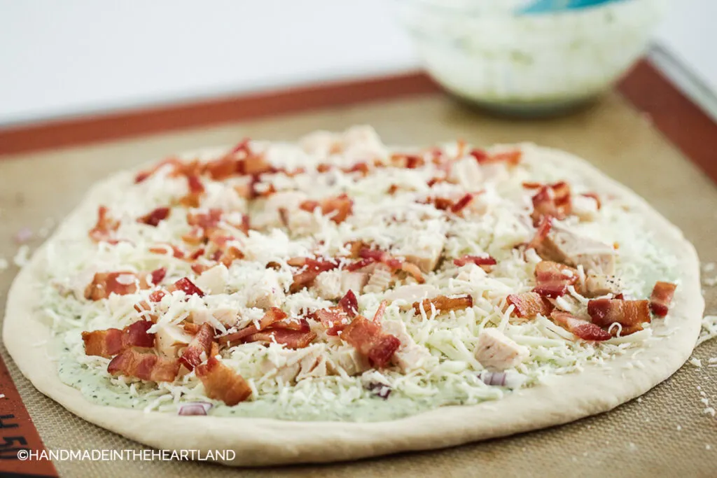 chicken bacon ranch pizza ready to be cooked sitting on a silpat nonstick baking liner
