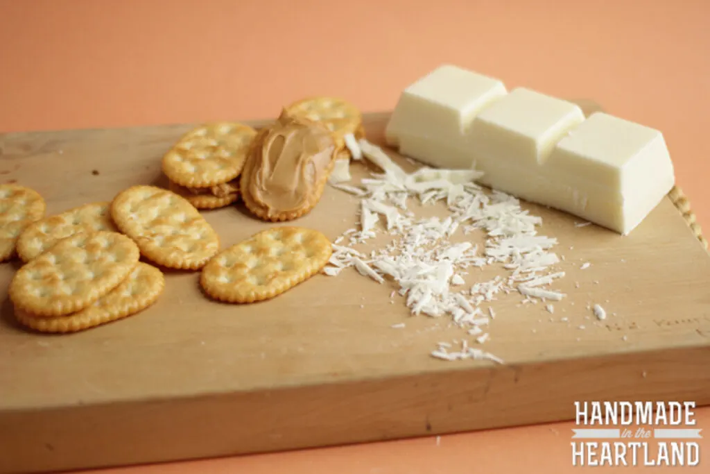 brick of vanilla almond bark and peanut butter spread on crackers sitting on a cutting board