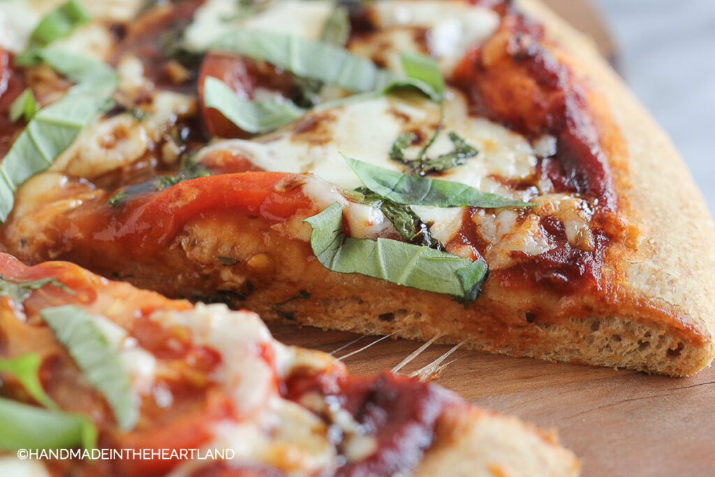 slices of homemade pizza with tomatoes, fresh basil, fresh mozzarella and balsamic glaze