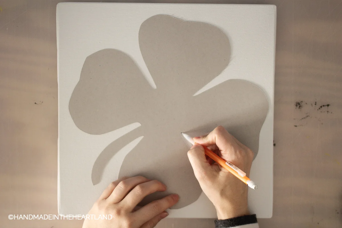 tracing chipboard shamrock onto white canvas