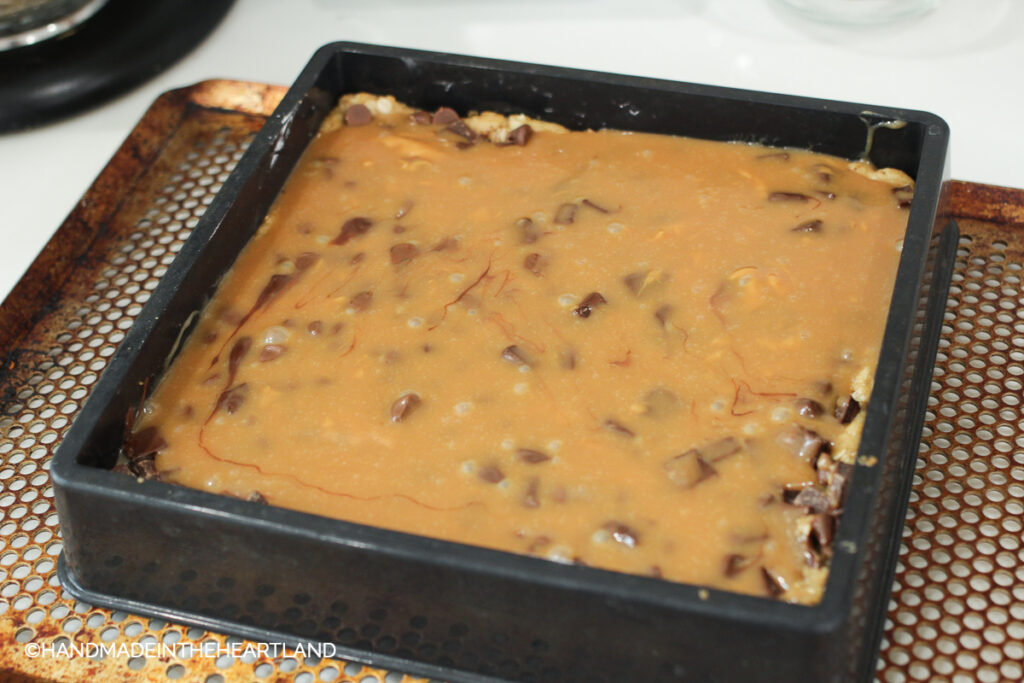 adding caramel sauce and chocolate chips to pre baked cookie crust