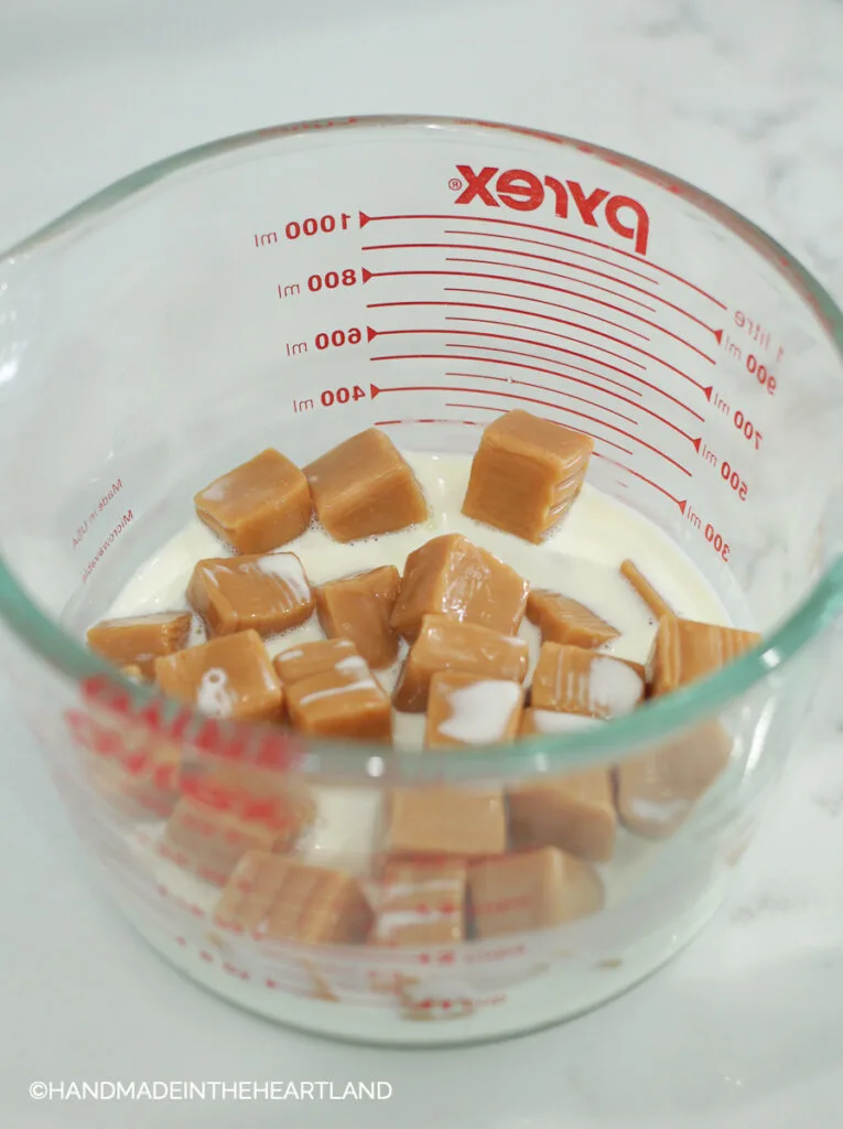 caramel candies and heavy whipping cream in a pyrex measuring cup, ready to melt to make caramel sauce
