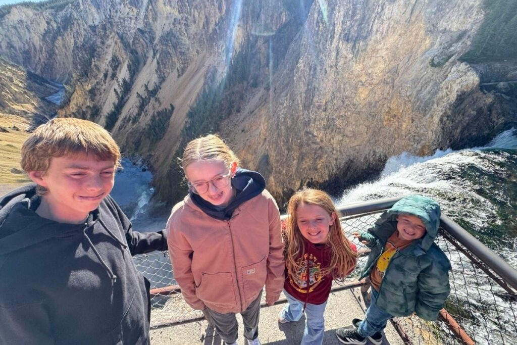 four kids at the brink of lower falls viewing point at the bottom of the trail in Yellowstone