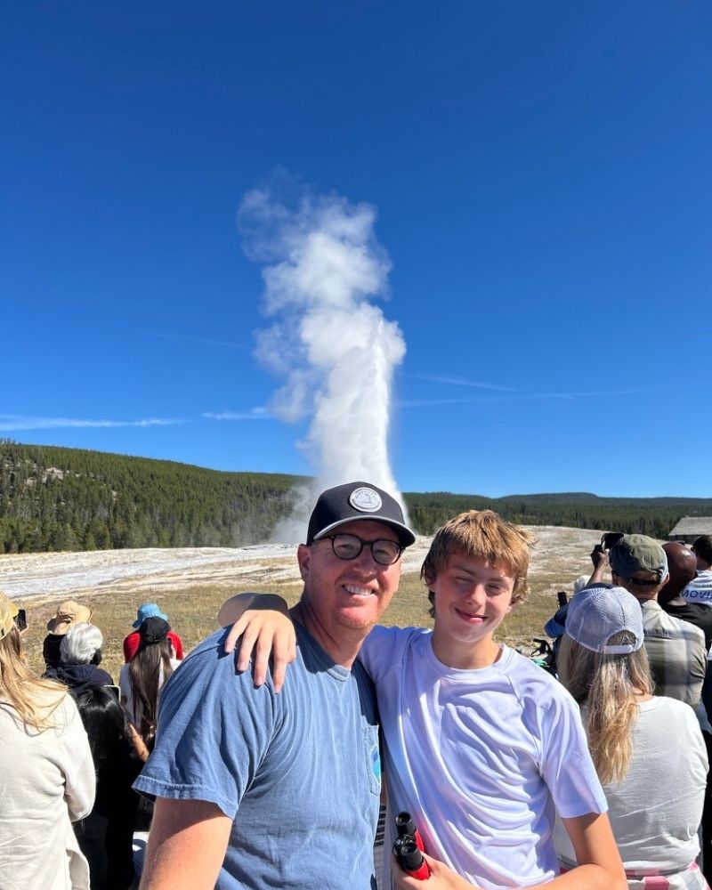 Father and son in front of Old Faithful in Yellowstone